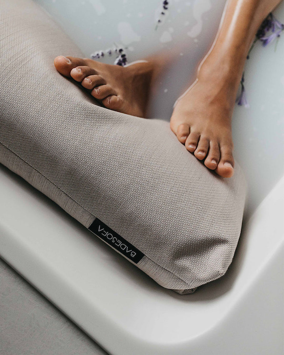Nahaufnahme, wie Füsse entspannt beim Baden auf einem Badesofa Fusskissen liegen.